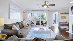 A spacious living room with a grey sofa, a coffee table, and a ceiling fan.