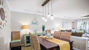 A dining area with a wooden table, wicker chairs, a chandelier, and a sign that reads "Lake".