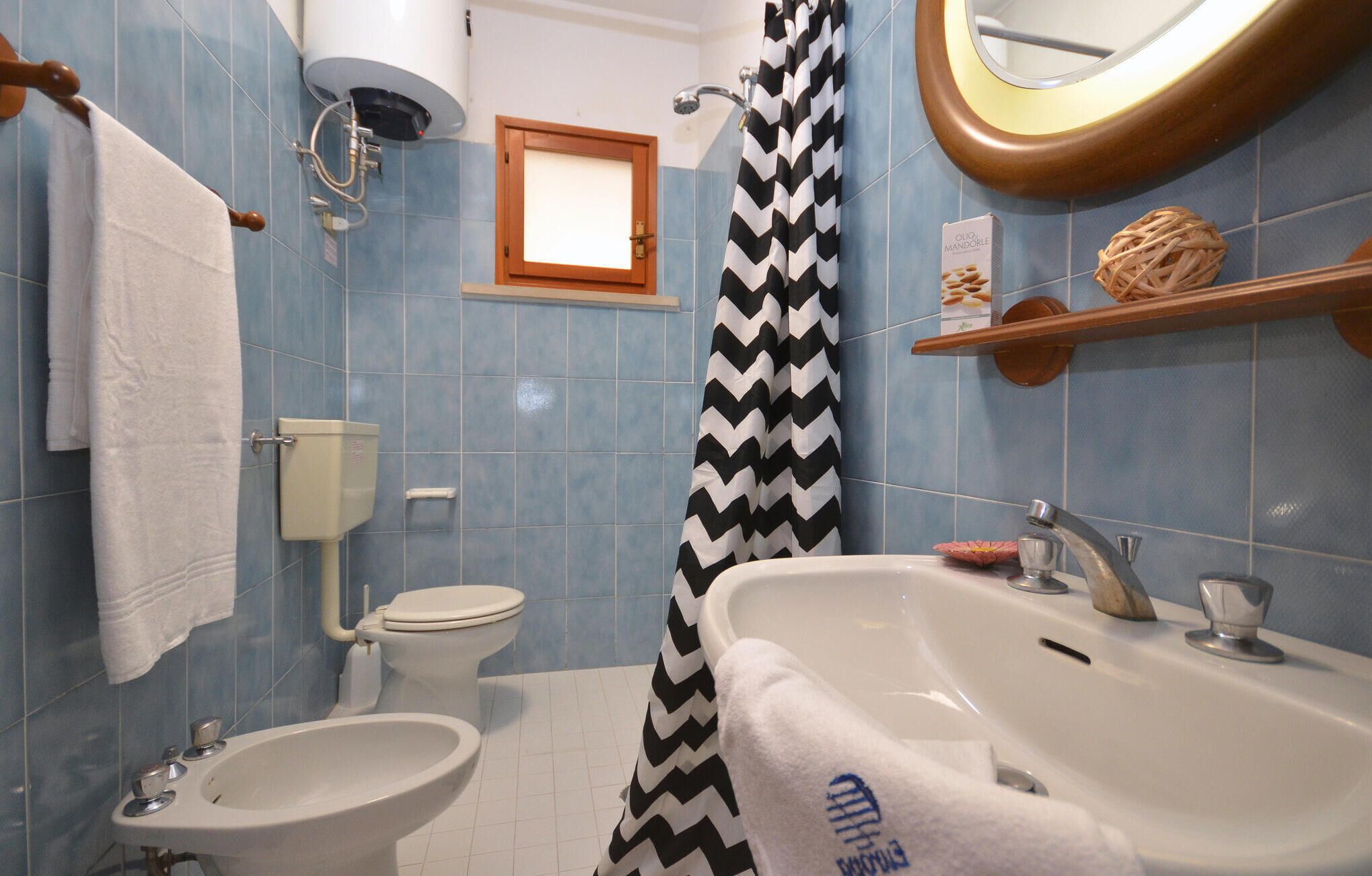 A bathroom with a toilet, bidet, sink, and shower curtain.