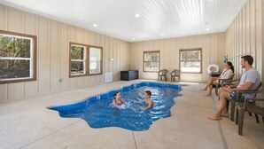 A swimming pool with a curved edge, surrounded by beige walls and windows. - Taneycomo Waterfront Retreat with Private Indoor Pool, Hot Tub, Game Room & $400 Daily Tickets (Branson)