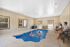 Una piscina con bordo curvo, circondata da pareti e finestre color beige.