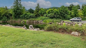 A serene outdoor setting with a body of water, rocks, and lush greenery. - Taneycomo Waterfront Retreat with Private Indoor Pool, Hot Tub, Game Room & $400 Daily Tickets (Branson)