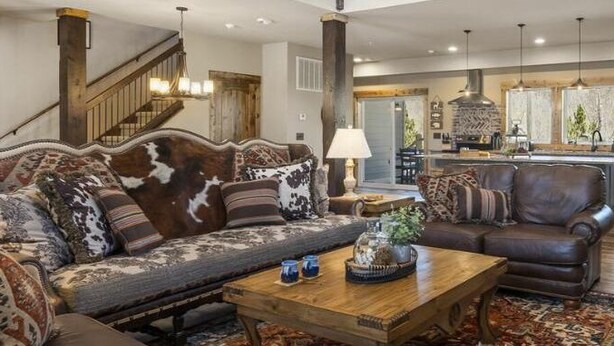 A spacious living room with a large sofa, a coffee table, and a fireplace. - Taneycomo Waterfront Retreat with Private Indoor Pool, Hot Tub, Game Room & $400 Daily Tickets (Branson)