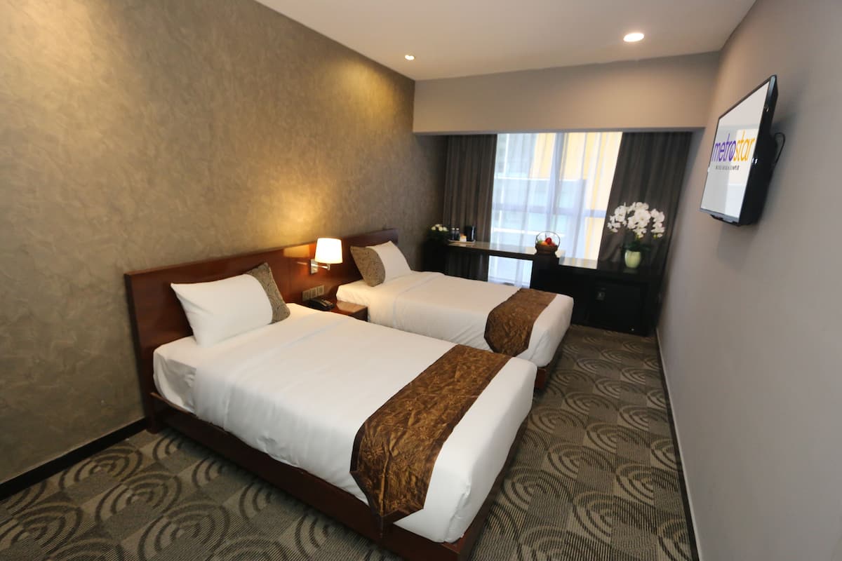 Een hotelkamer met twee bedden, een televisie, een bureau en een raam met gordijnen.