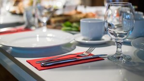 Une table à manger dressée avec des assiettes, des couverts et un verre à vin.