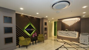 Un hall d’hôtel moderne comprenant un comptoir d’accueil, un espace salon et des panneaux muraux décoratifs.