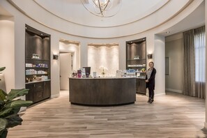 A modern reception area with a central counter, shelves with products, and a circular ceiling design.