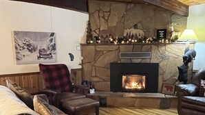 Ein gemütliches Wohnzimmer mit Kamin aus Stein, Holzböden und Ledersofas.