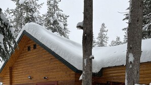 Eine Blockhütte mit verschneitem Dach und einer Holzterrasse.