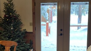 Ein Essbereich mit einem Holztisch und Stühlen, einem Weihnachtsbaum und einer zur Außenseite führenden Tür.