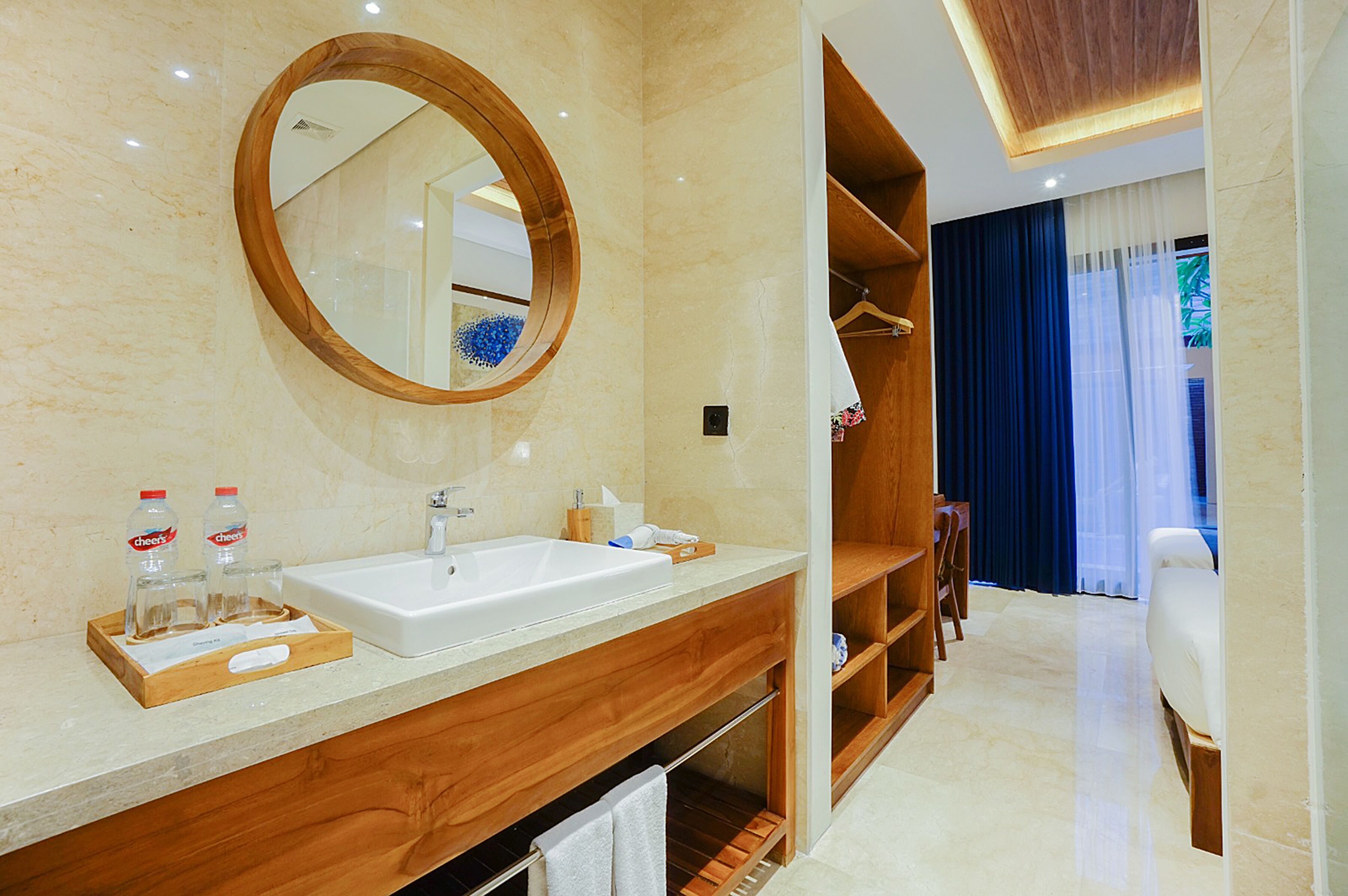 A modern bathroom with a wooden vanity, a large mirror, and a white sink.