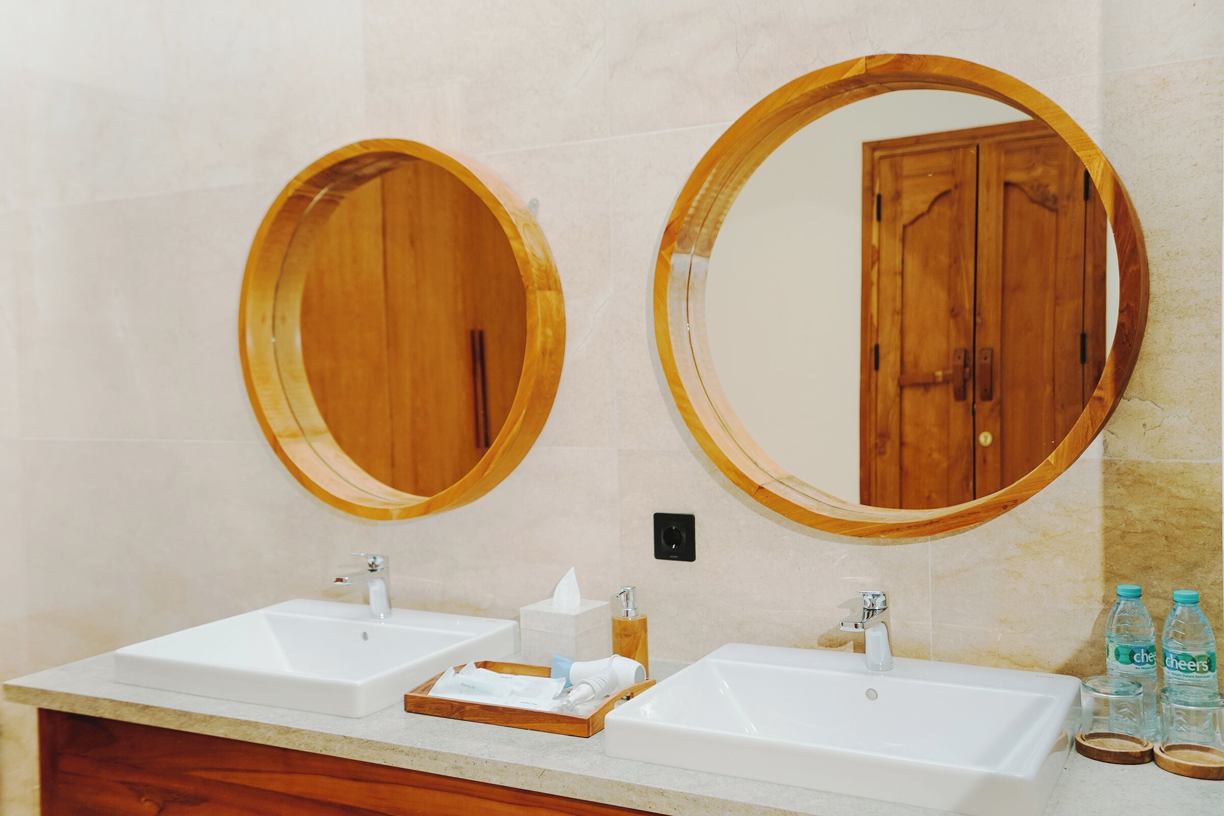 A bathroom with two sinks, wooden-framed mirrors, and a wooden vanity.