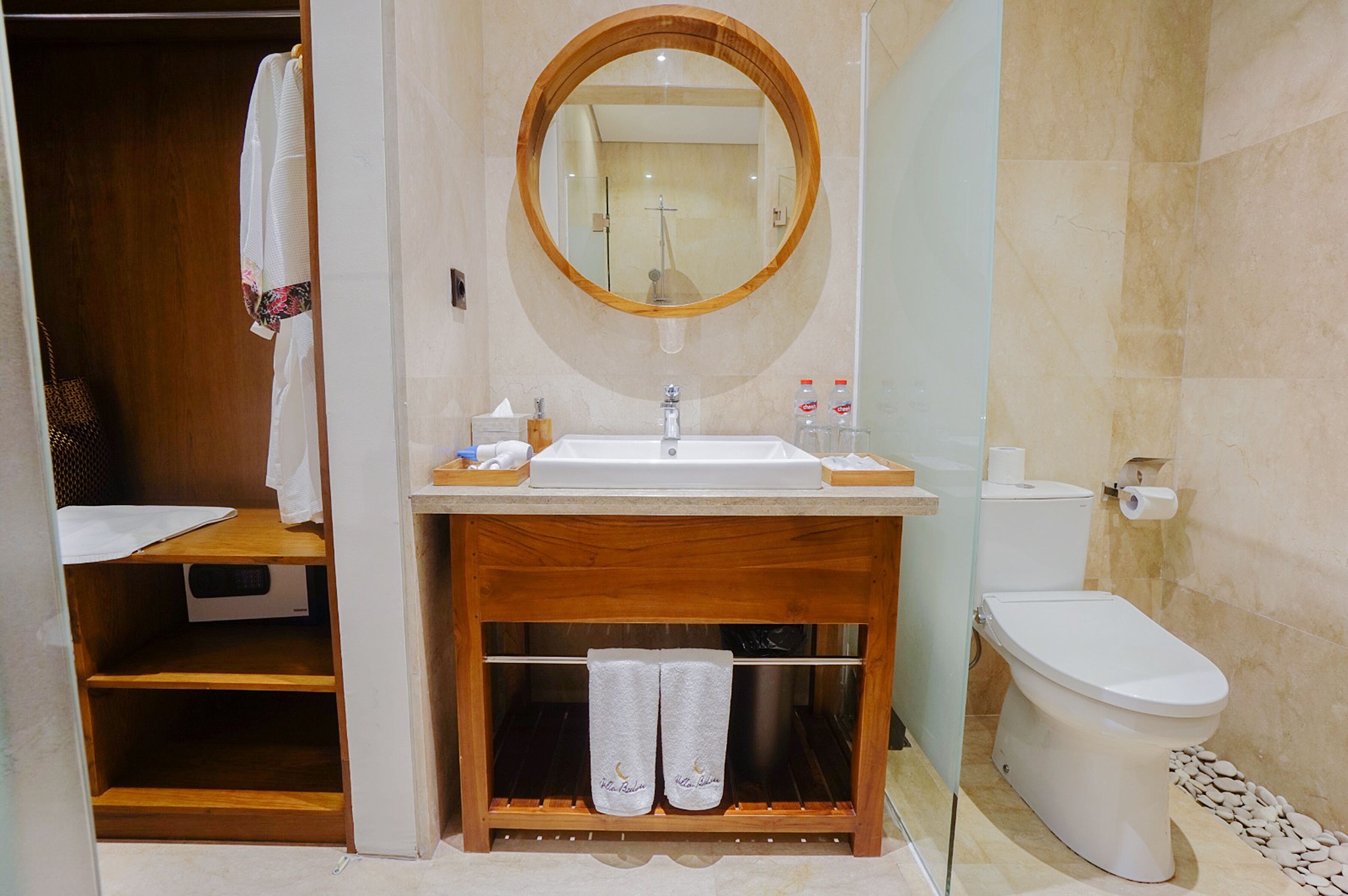 A bathroom with a wooden vanity, a sink, a mirror, and a toilet.