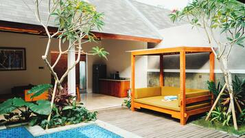 A modern outdoor living area with a wooden deck, a small pool, and a wooden canopy bed.