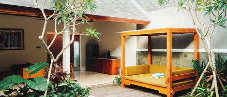 A modern outdoor living area with a wooden deck, a small pool, and a wooden canopy bed.