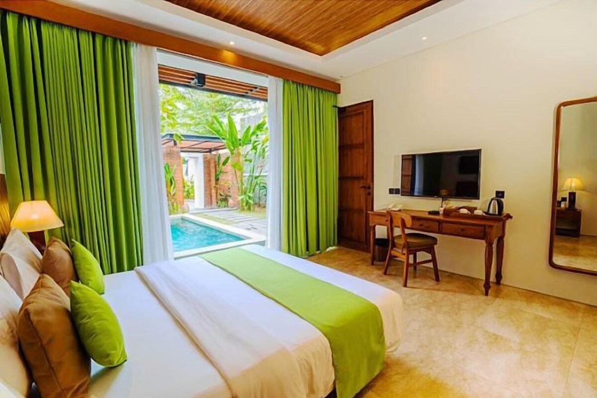 Habitación de hotel con cama, escritorio, silla, televisión y vista a una piscina.