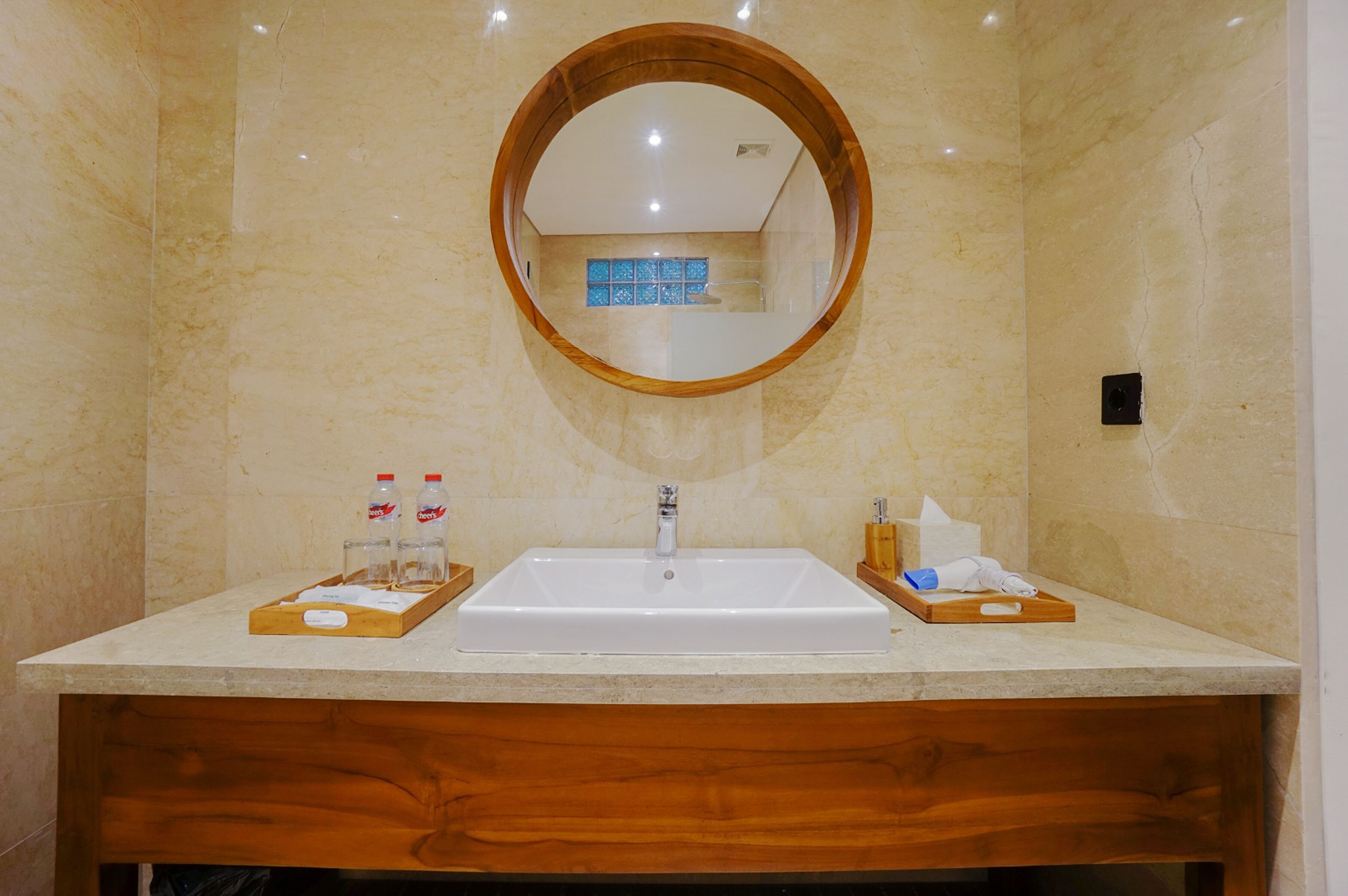 A bathroom with a large mirror, a sink, and two wooden side tables with toiletries.