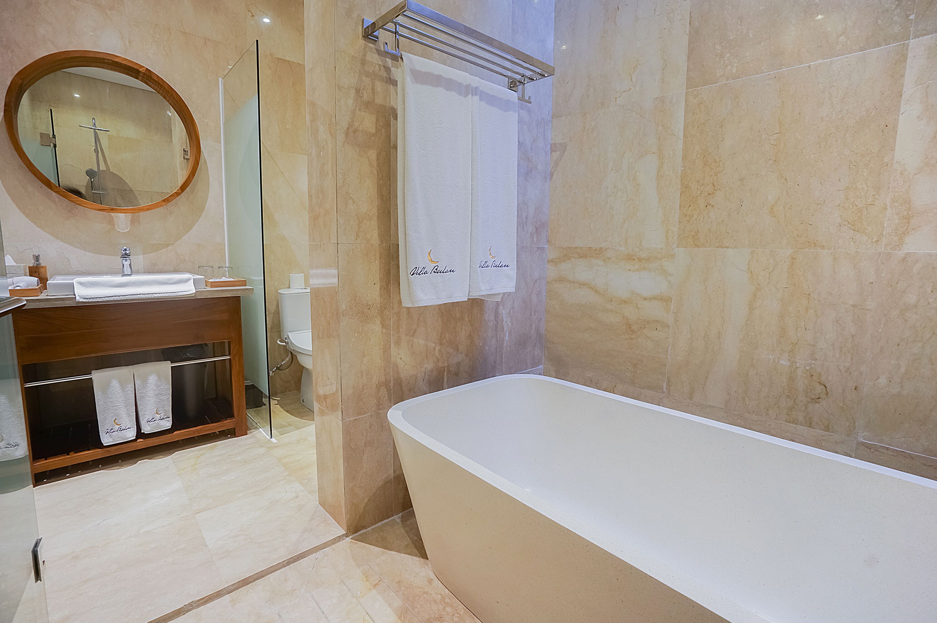A modern bathroom with a freestanding bathtub, a vanity with a mirror, and two towels hanging on the wall.