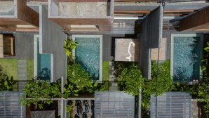 A modern building with multiple balconies, each with a glass enclosure and greenery. - Villa Bulan Bali (Jimbaran)