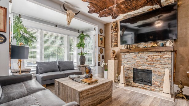 Een moderne woonkamer met een stenen openhaard, leren banken en een aan de muur bevestigde televisie.