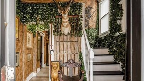 Een trap met houten leuning, omgeven door groen en decoratieve details.