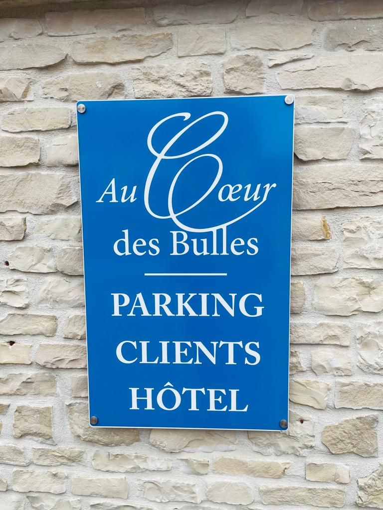 A blue sign with white text on a stone wall.