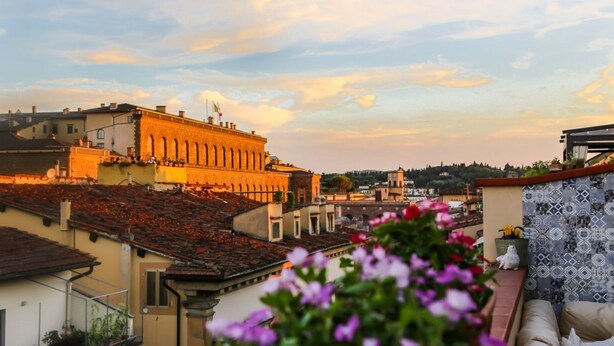Un edificio con tejado de tejas, un balcón con flores y vistas a la ciudad.