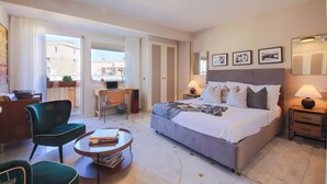 Habitación de hotel con cama, escritorio, silla, mesa de centro y vistas al exterior.