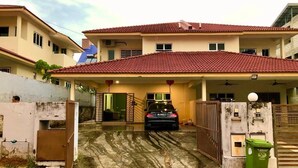 A two-story house with a red-tiled roof, a covered carport, and a gated entrance. - MUTIARA HEIGHT HOMESTAY  (Bentong)