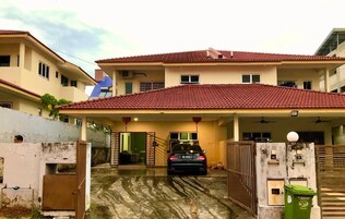 Una casa de dos pisos con techo de tejas rojas, un garaje cubierto y una entrada con portón.