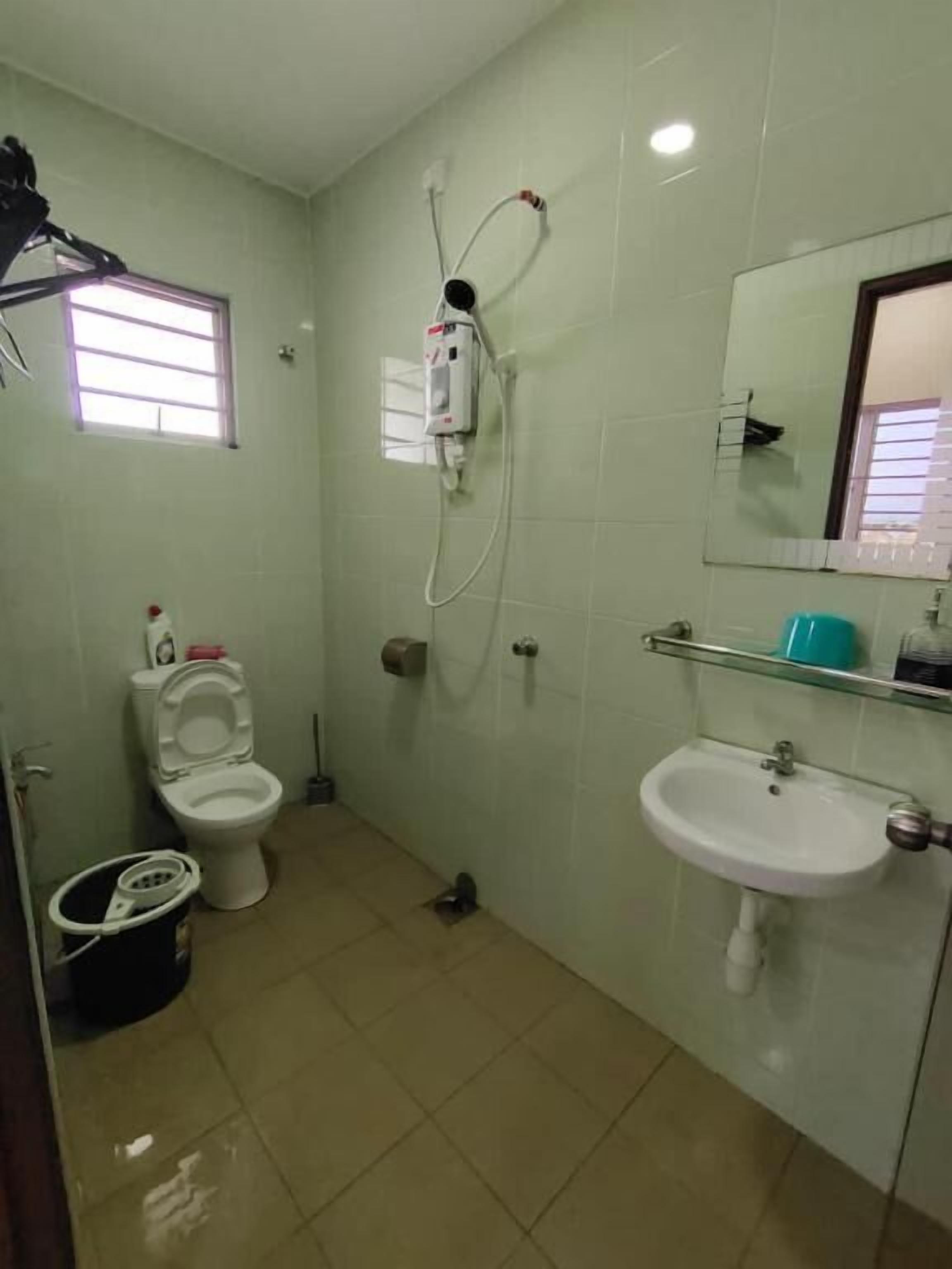 Un baño con inodoro, bidé, lavamanos y ducha con cabezal de ducha manual.