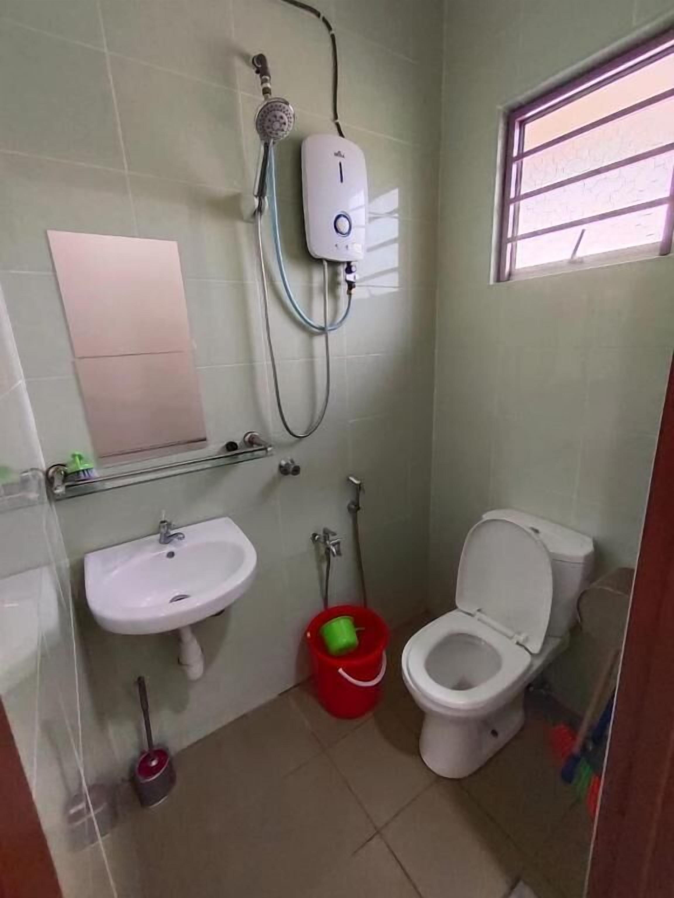 A small bathroom with a toilet, sink, and shower.