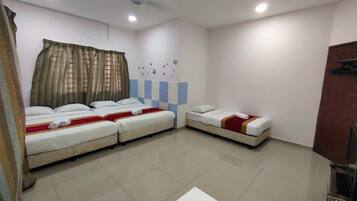 A hotel room with three beds arranged in a U-shape, a ceiling fan, and a tiled floor.