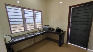 A compact kitchen with a sink, stove, and window overlooking a scenic view. - MUTIARA HEIGHT HOMESTAY  (Bentong)