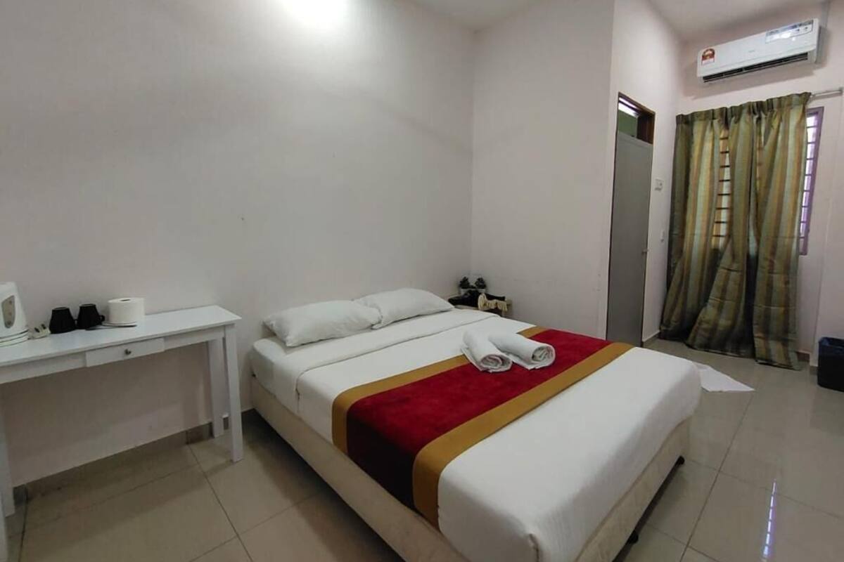 A hotel room with a bed, a desk, a chair, and a window with curtains.