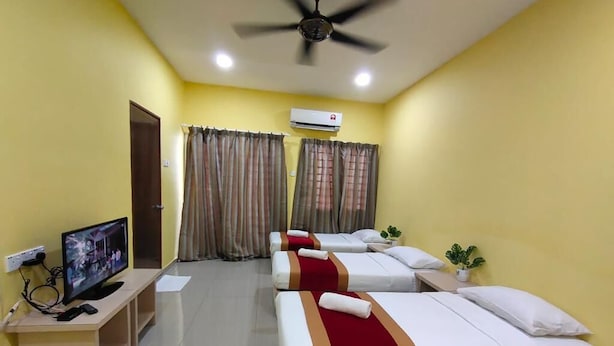 A hotel room with three beds, a TV, a desk, and an air conditioning unit. - MUTIARA HEIGHT HOMESTAY  (Bentong)
