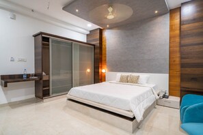 A modern bedroom with a large bed, a wardrobe, a bedside table, and a blue chair.