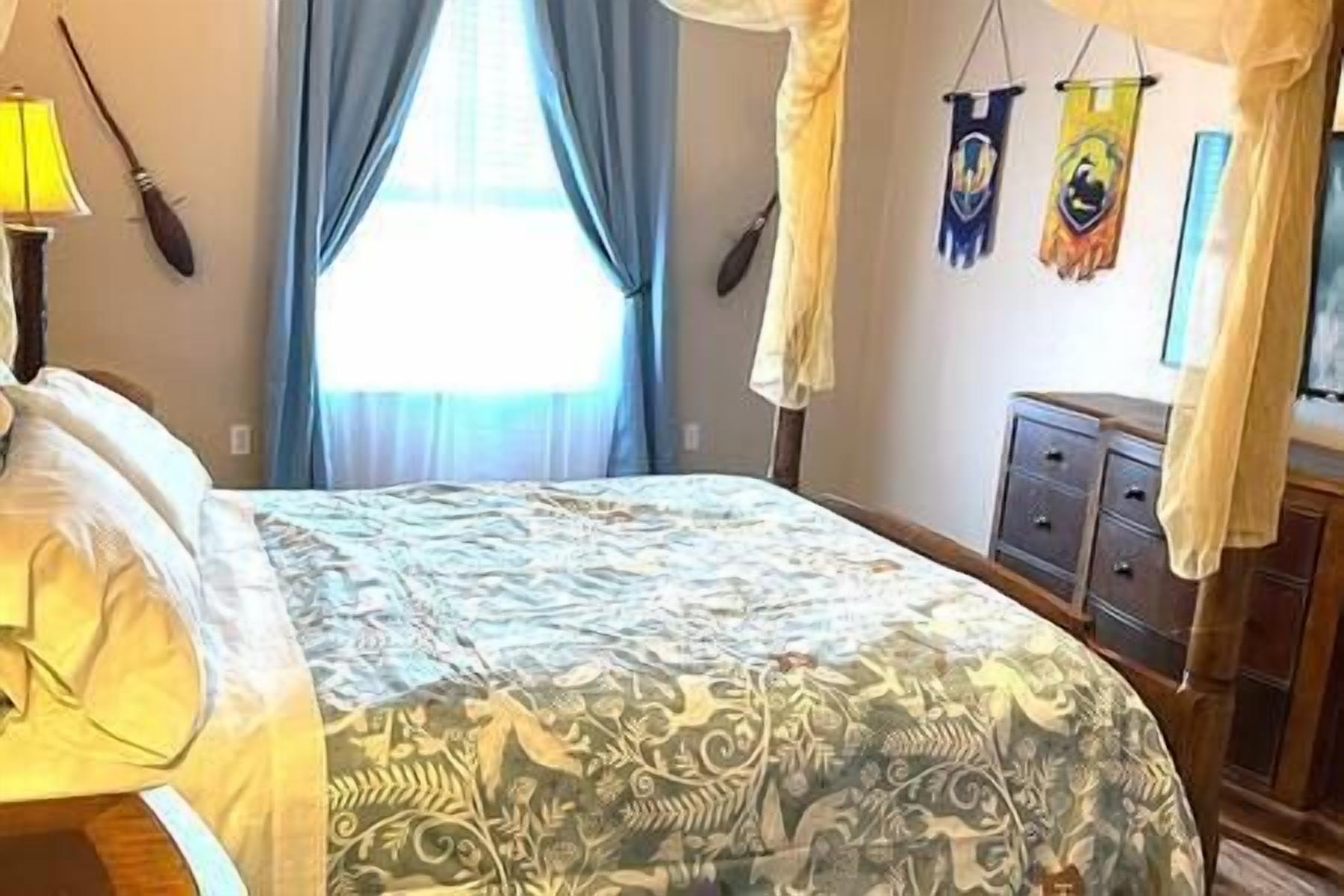Een slaapkamer met een bed, gordijnen, een nachtkastje en een dressoir.