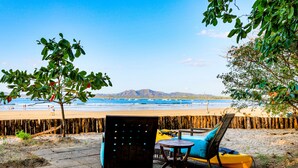 A beachside seating area with a view of the ocean and mountains.
