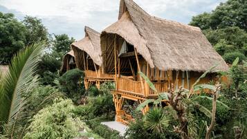 Edificio tradizionale con tetto di paglia e un balcone in legno, immerso nel verde.