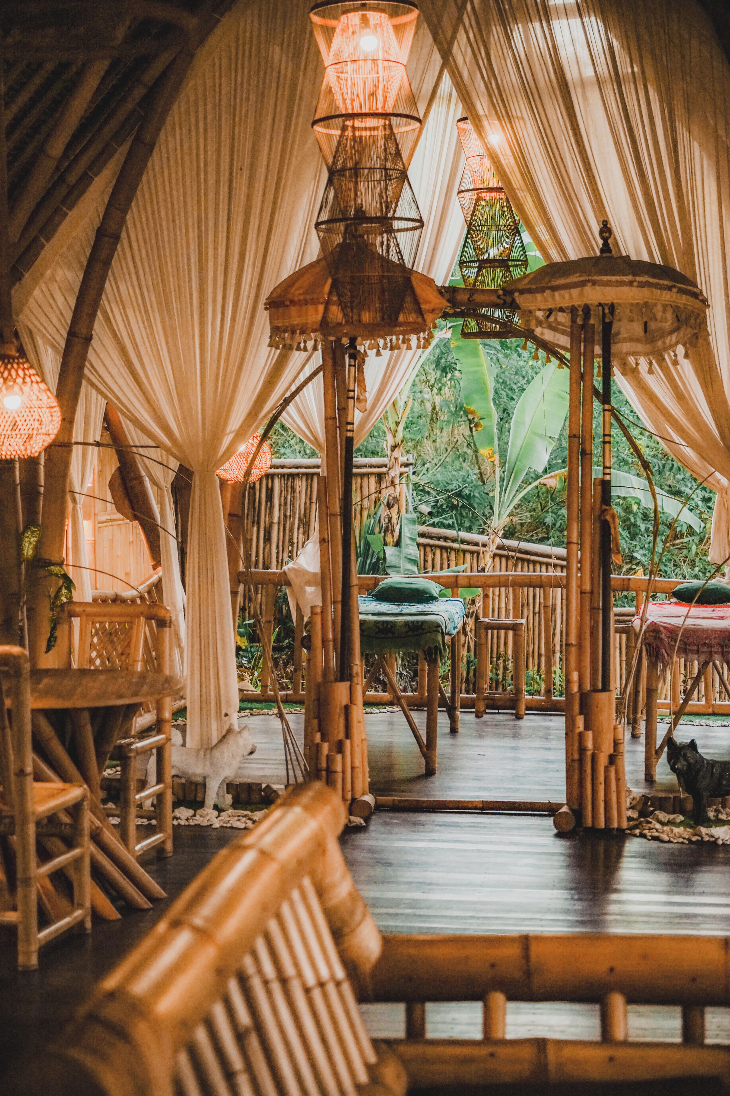 An indoor venue with bamboo furniture, a central seating area, and hanging lamps.