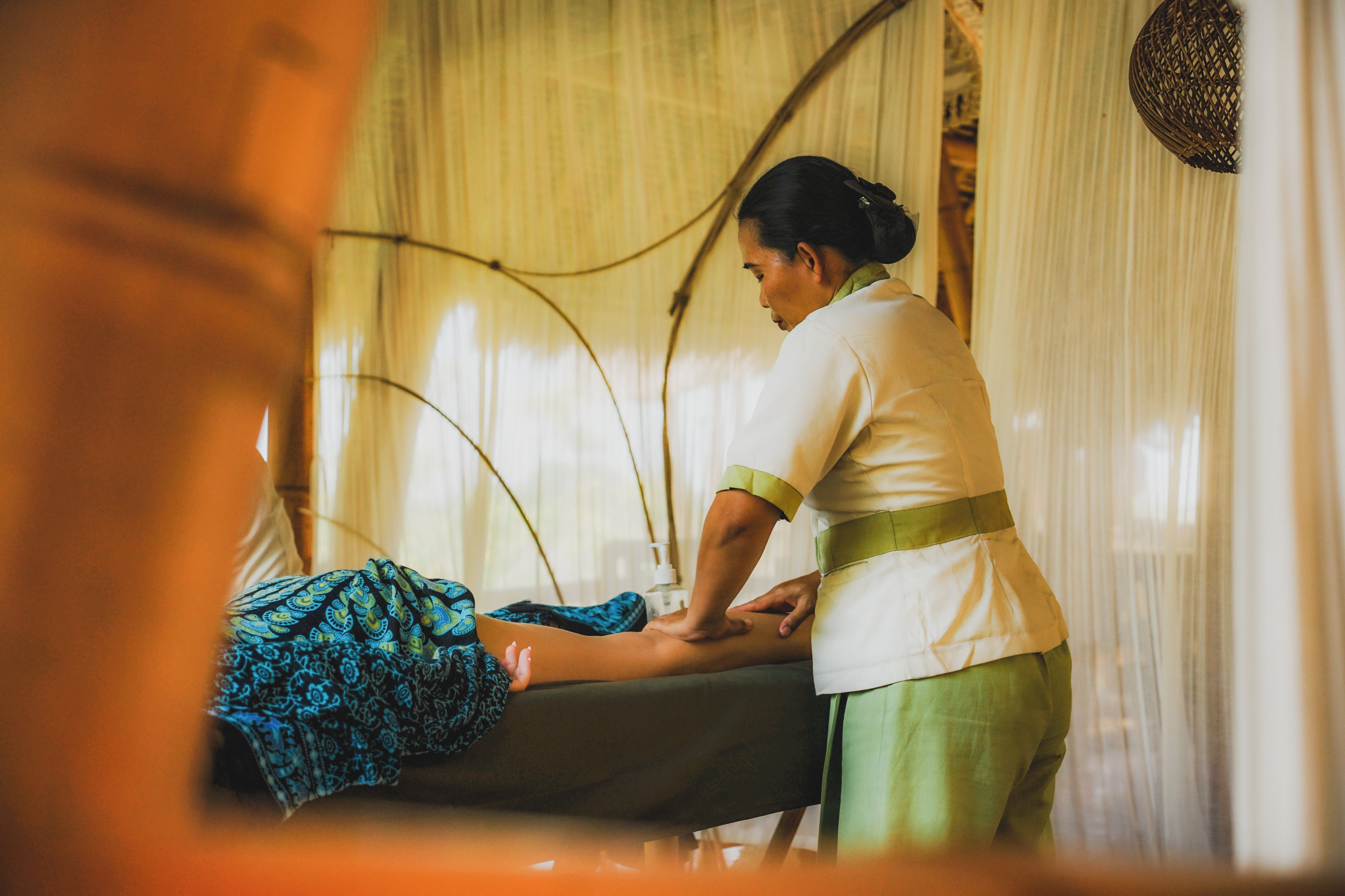 Sesión de terapia de masajes en una habitación con cama, camilla y cortina.