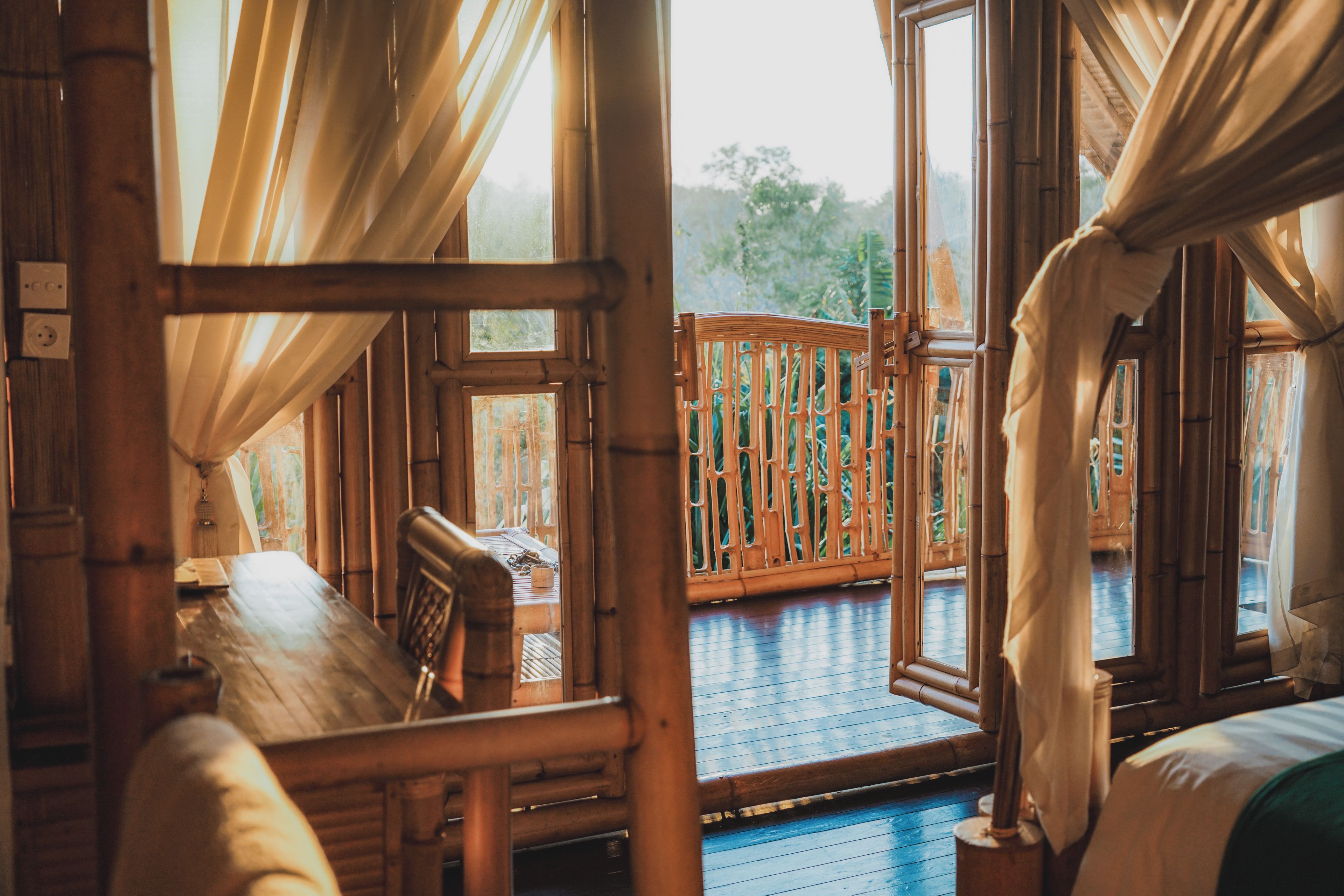 Ein Zimmer mit Holzboden, einem Bett mit Kopfteil, einer Holzbank und Blick auf eine Holzterrasse.
