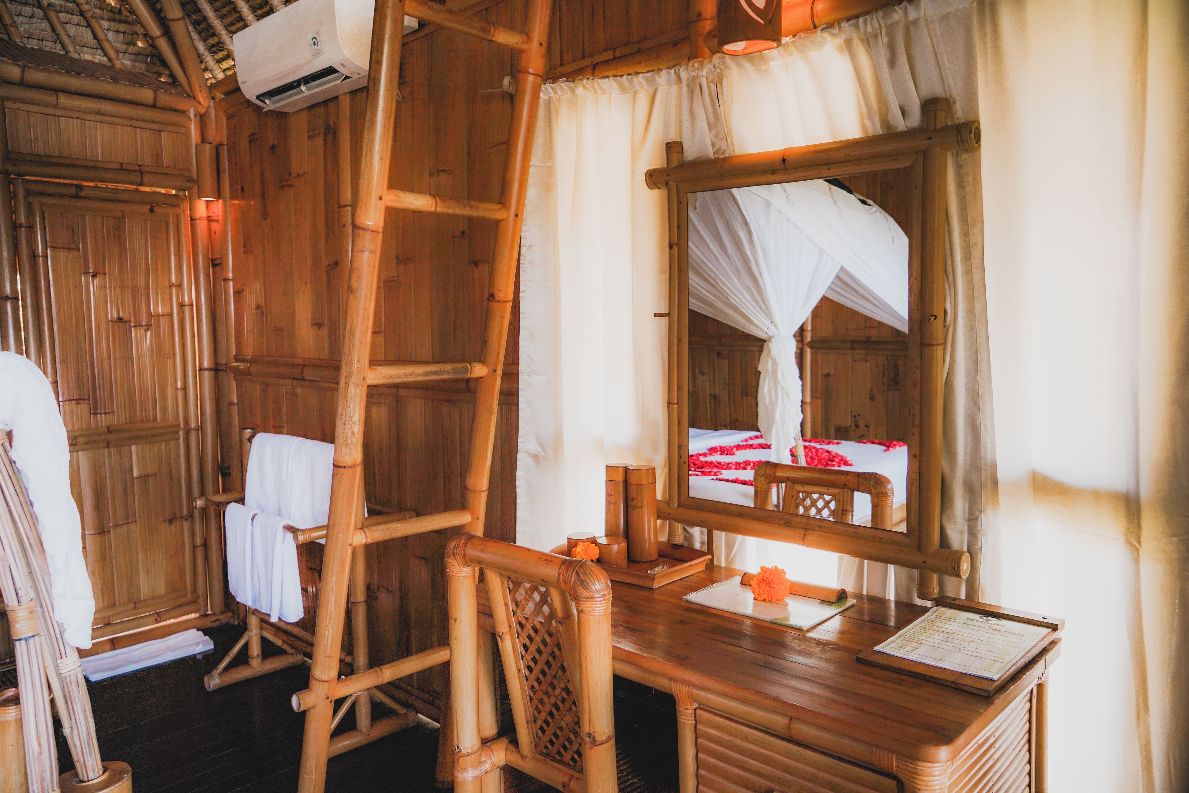 A wooden room with a bed, a ladder, a desk, and a mirror.