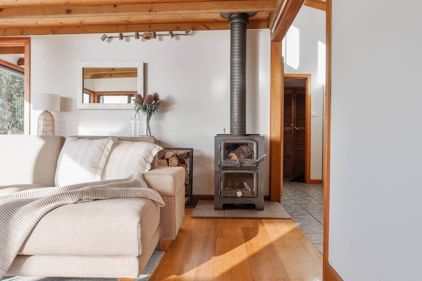 A cozy room with a sofa, a wooden floor, a fireplace, and a window.