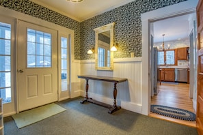 Enter a homey hallway with a large mirror, floral wallpaper, and a console table.