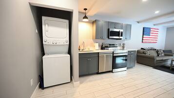 A modern kitchen with grey cabinets, stainless steel appliances, and a white washing machine.