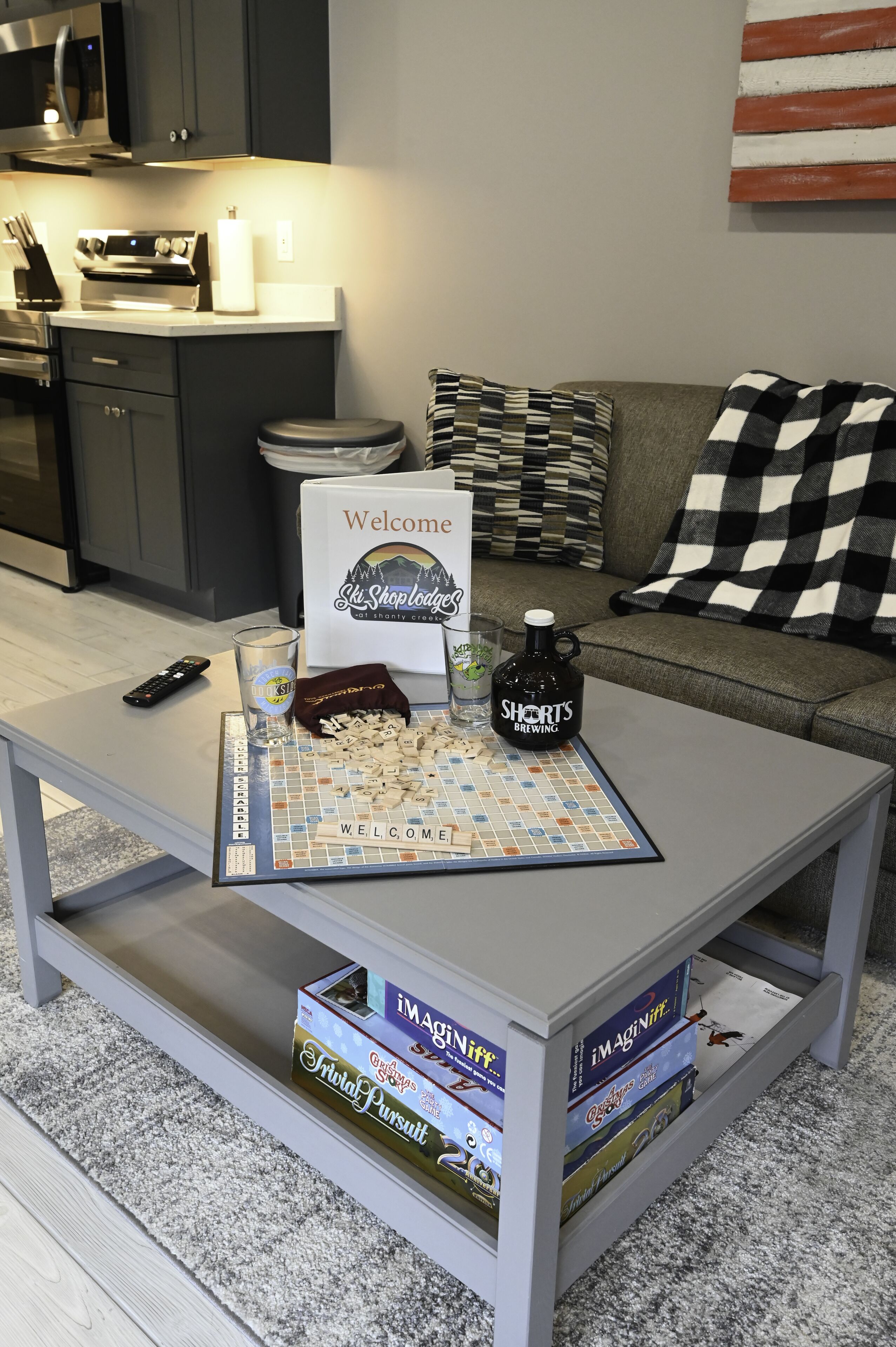 Sala de estar com uma mesa de centro exibindo um jogo de tabuleiro, um controle remoto e uma garrafa de bebida.