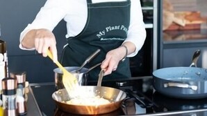 A person cooking in a modern kitchen with stainless steel appliances and a black countertop. - Unique Boutique luxury Bed and Breakfast (Chichester)