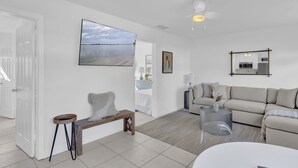 Ein modernes Wohnzimmer mit großem Flachbildfernseher, einer Couch, einer Bank und einem runden Couchtisch.